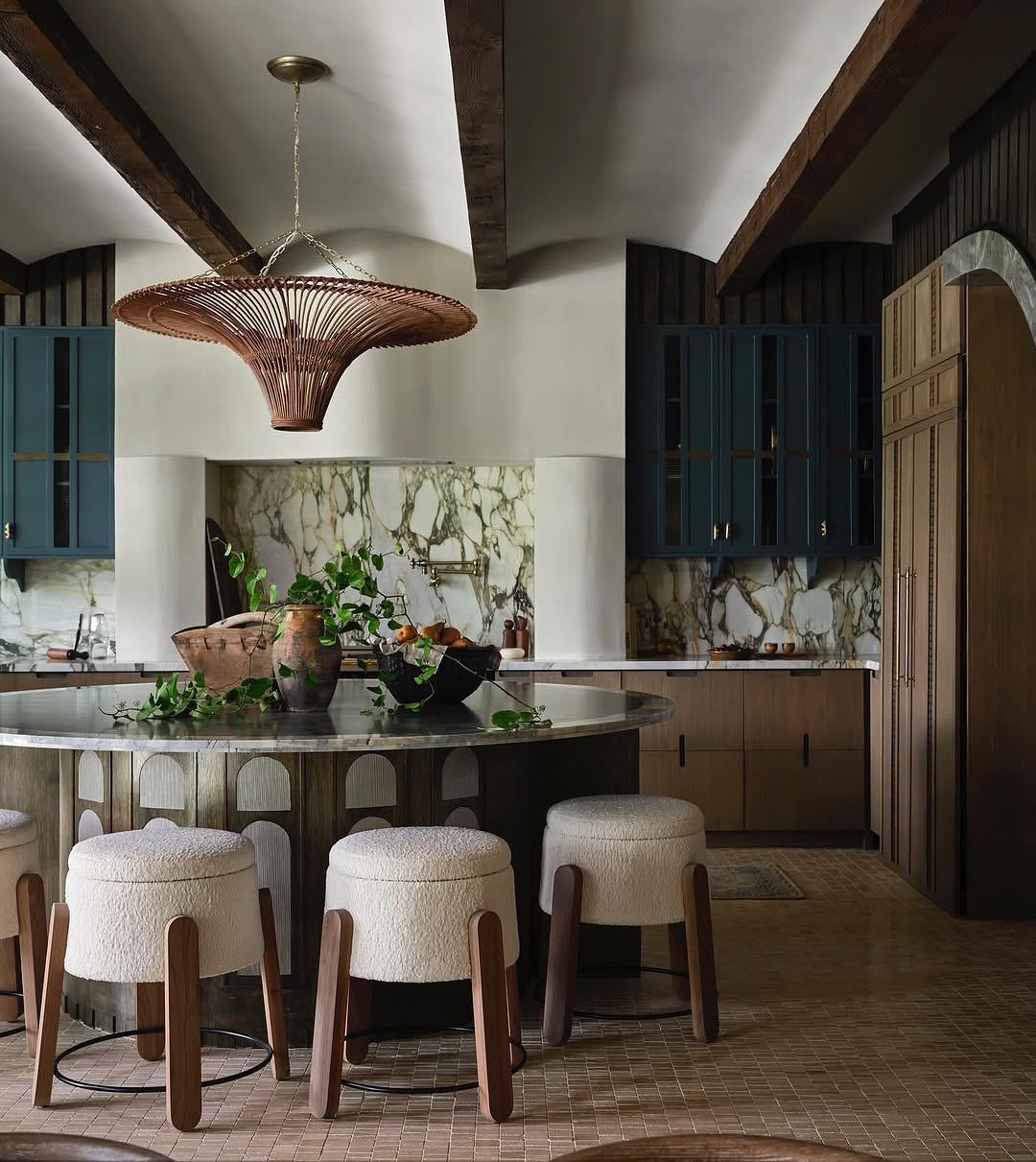 Luxurious kitchen featuring large rounded island and cool stools